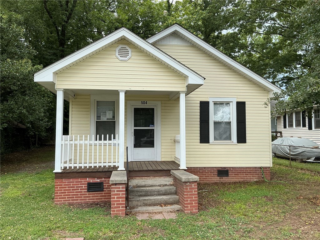 A charming single-story residence with a welcoming front porch and classic brick foundation.
