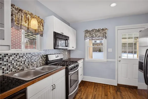 a kitchen with granite countertop a stove a sink and wooden floors