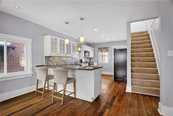 a kitchen with stainless steel appliances granite countertop a kitchen island hardwood floor and a sink