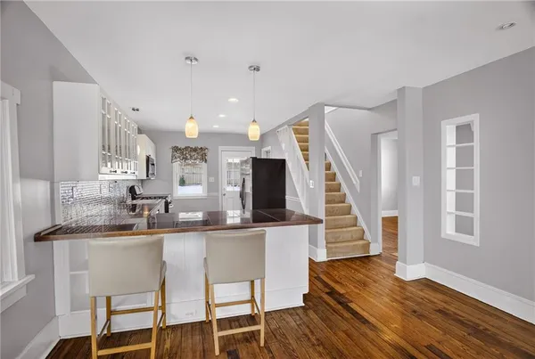 a kitchen with stainless steel appliances kitchen island wooden floors and white cabinets