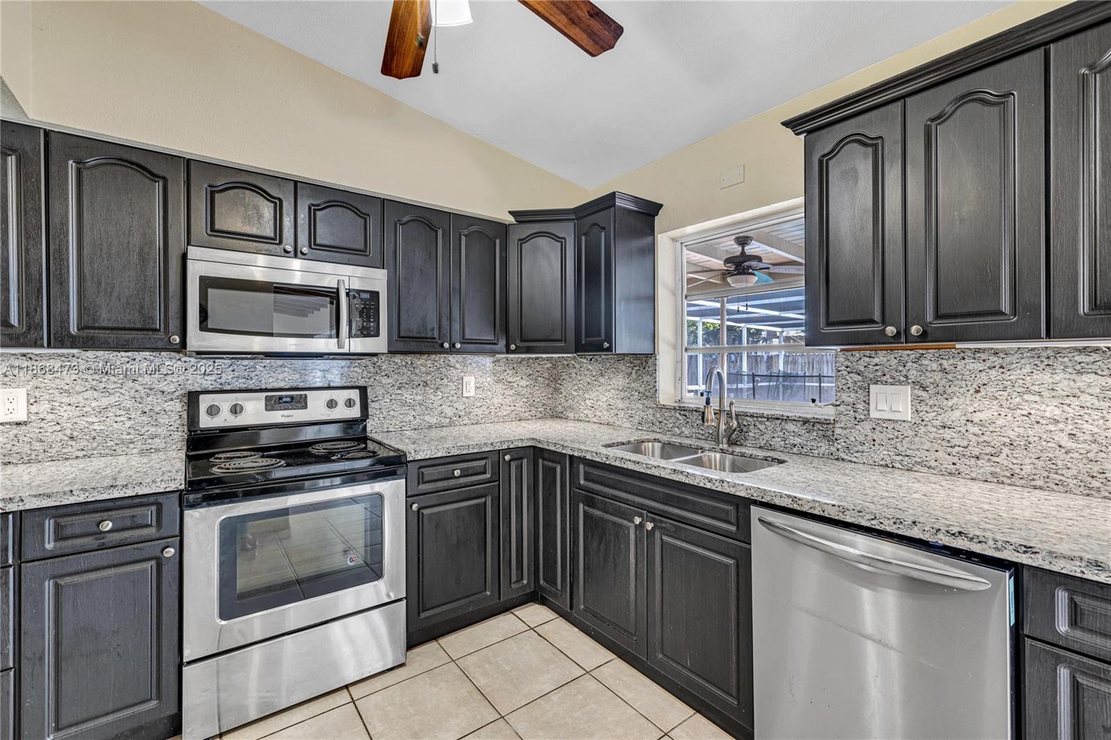 650 Northeast 178th Street Miami, FL 33162 - Photo 14 of 37 a kitchen with granite countertop a sink dishwasher stove and microwave with wooden cabinets