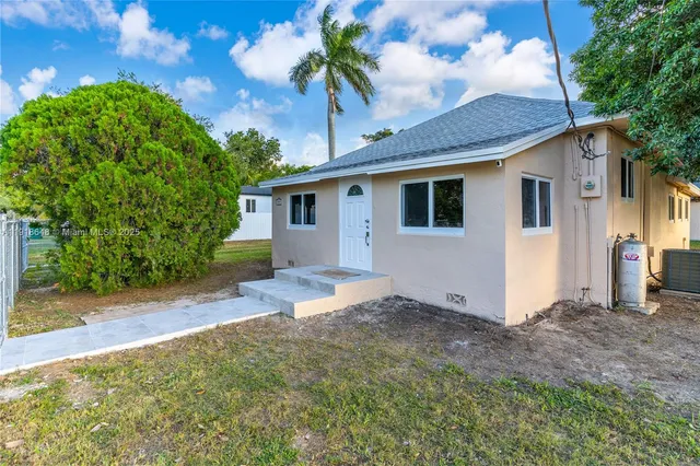 a large white kitchen with kitchen island a stove a refrigerator cabinets and living room view