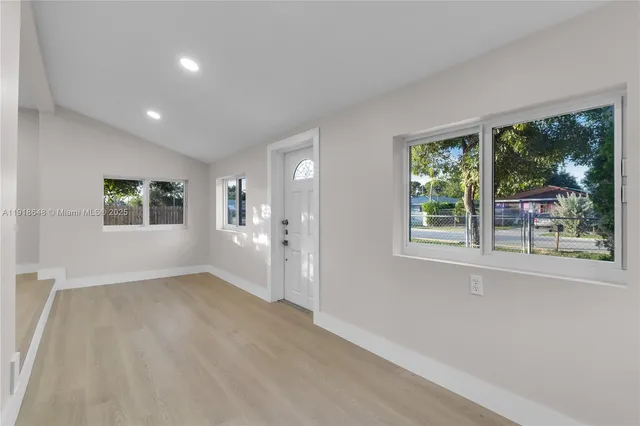 a kitchen with stainless steel appliances granite countertop a sink a stove a refrigerator and white cabinets