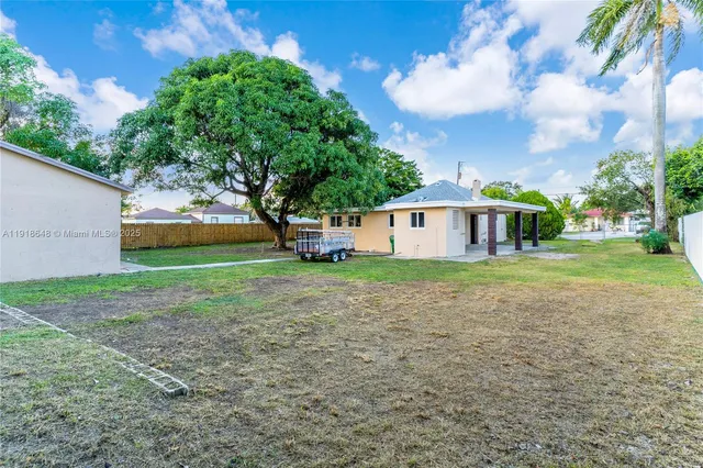 a view of backyard with potted plants and large tree