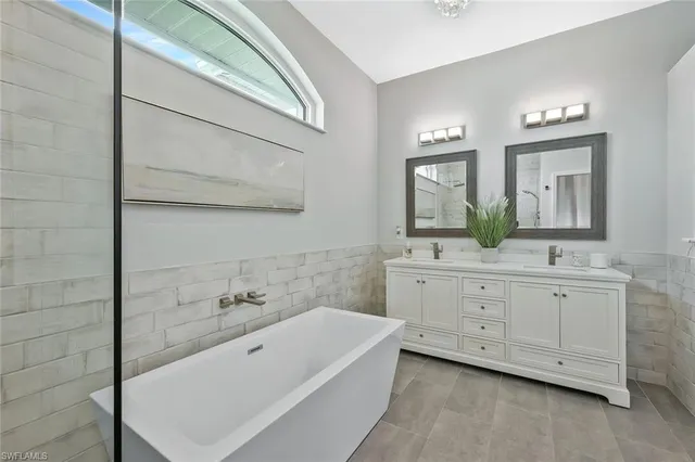 a bathroom with a double vanity sink a mirror and a bathtub
