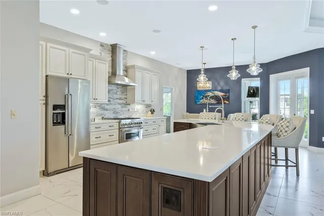 a large kitchen with kitchen island a large counter top appliances and cabinets