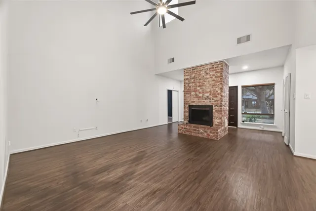 an empty room with wooden floor fireplace and windows