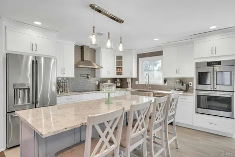 a kitchen with stainless steel appliances granite countertop a table chairs sink refrigerator and microwave