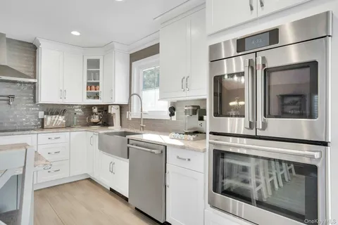 a kitchen with a stove white cabinets sink and refrigerator