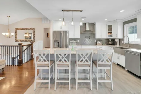 a kitchen with stainless steel appliances kitchen island granite countertop a dining table chairs and view living room