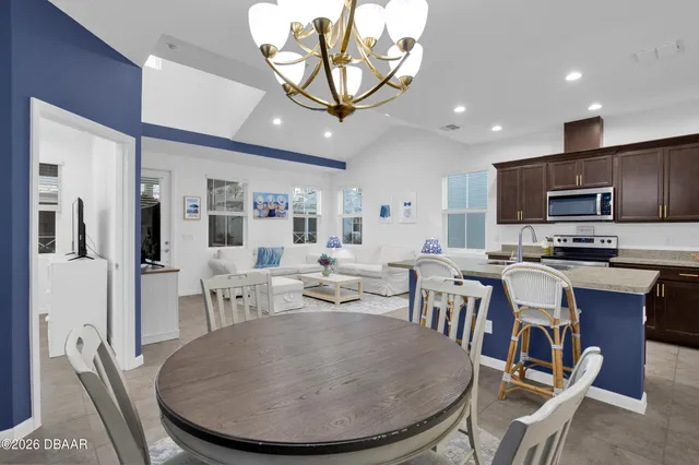 a living room with stainless steel appliances furniture a dining table and kitchen view