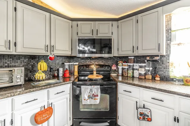 a kitchen with stainless steel appliances granite countertop a stove a sink and a white cabinets