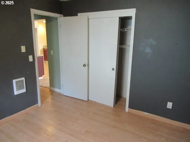 a view of an empty room with closet and a bathroom