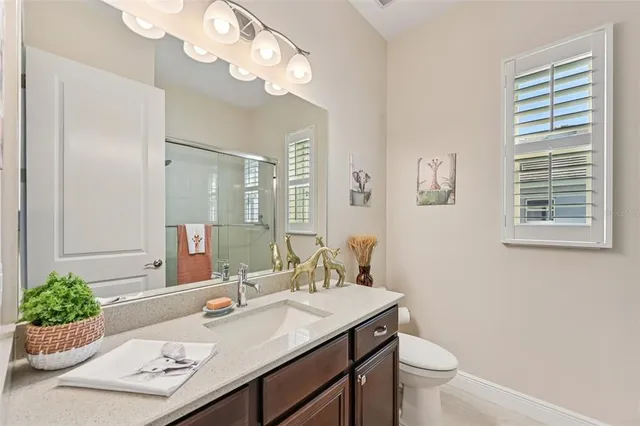 a bathroom with a granite countertop sink vanity mirror and toilet