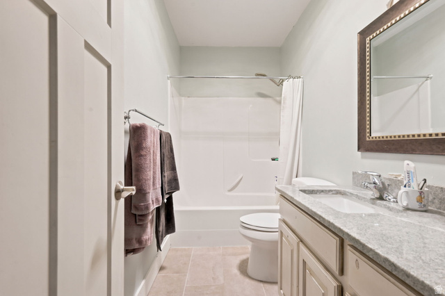 580 North 300 East Logan, UT 84321 - Photo 42 of 74 Bathroom featuring a white tub and shower combination, a vanity with a light-colored countertop and integrated sink, a large framed mirror, and light-toned floor tiles
