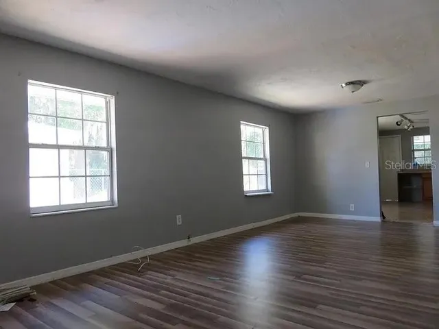 an empty room with wooden floor and windows