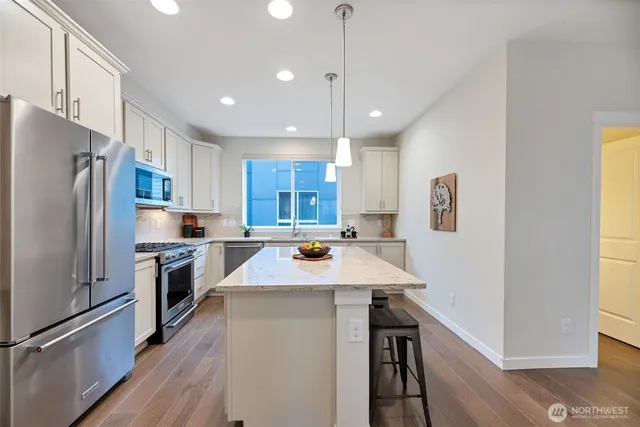 a kitchen with stainless steel appliances kitchen island a refrigerator sink and wooden floor