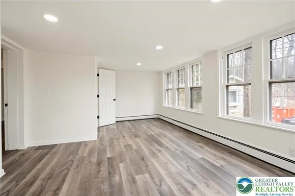 a view of an empty room with wooden floor and a window