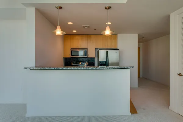 a view of hallway with granite countertop cabinets and a refrigerator