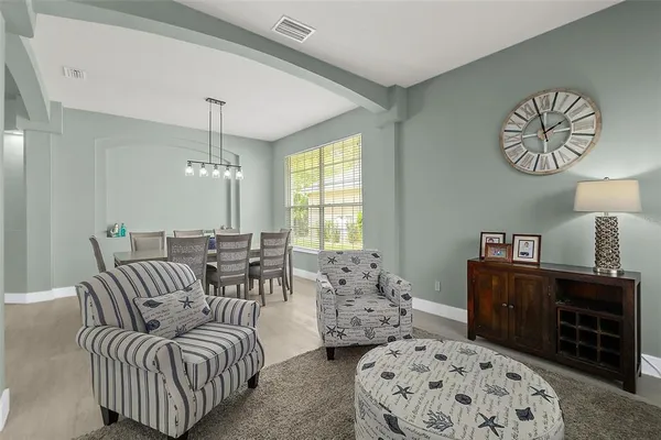 a living room with furniture kitchen view and a chandelier