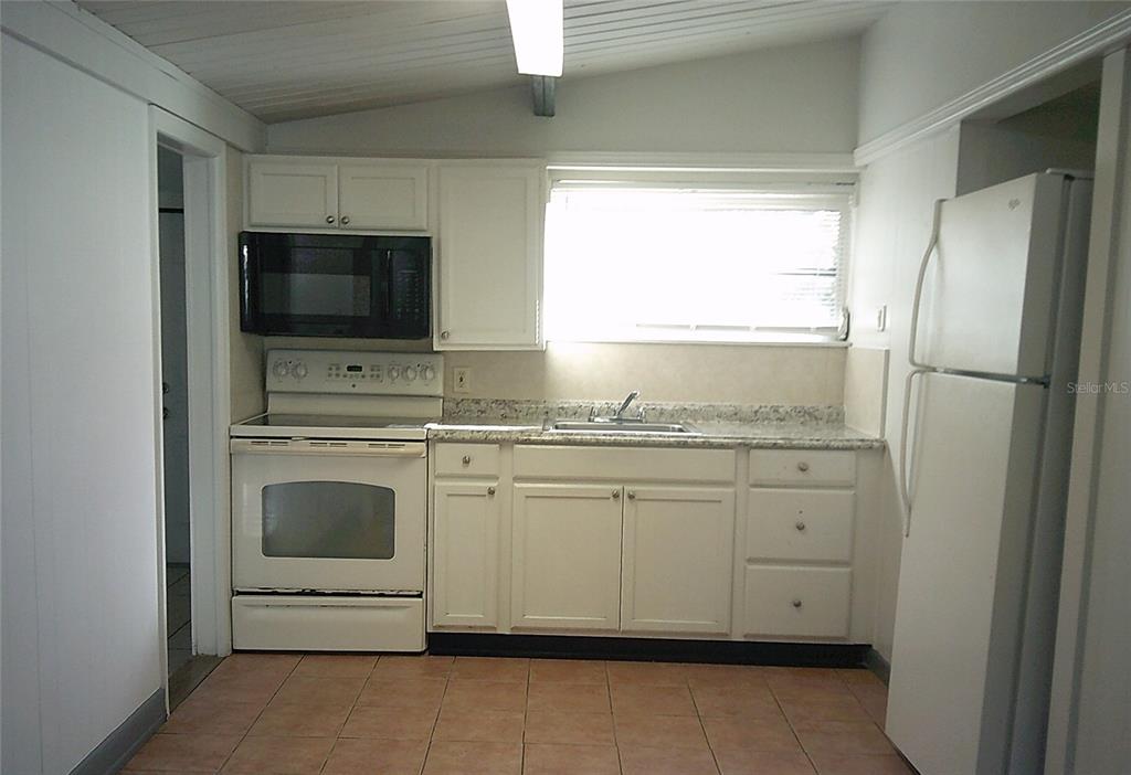 1060 65th Street South St. Petersburg, FL 33707 - Photo 6 of 20 a kitchen with granite countertop a sink stainless steel appliances and cabinets