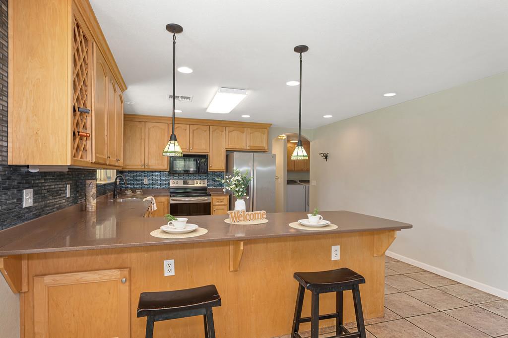 6181 Lambert Lane El Dorado, CA 95623 - Photo 26 of 68 kitchen with a peninsula, stainless steel appliances, a kitchen breakfast bar, and hanging light fixtures