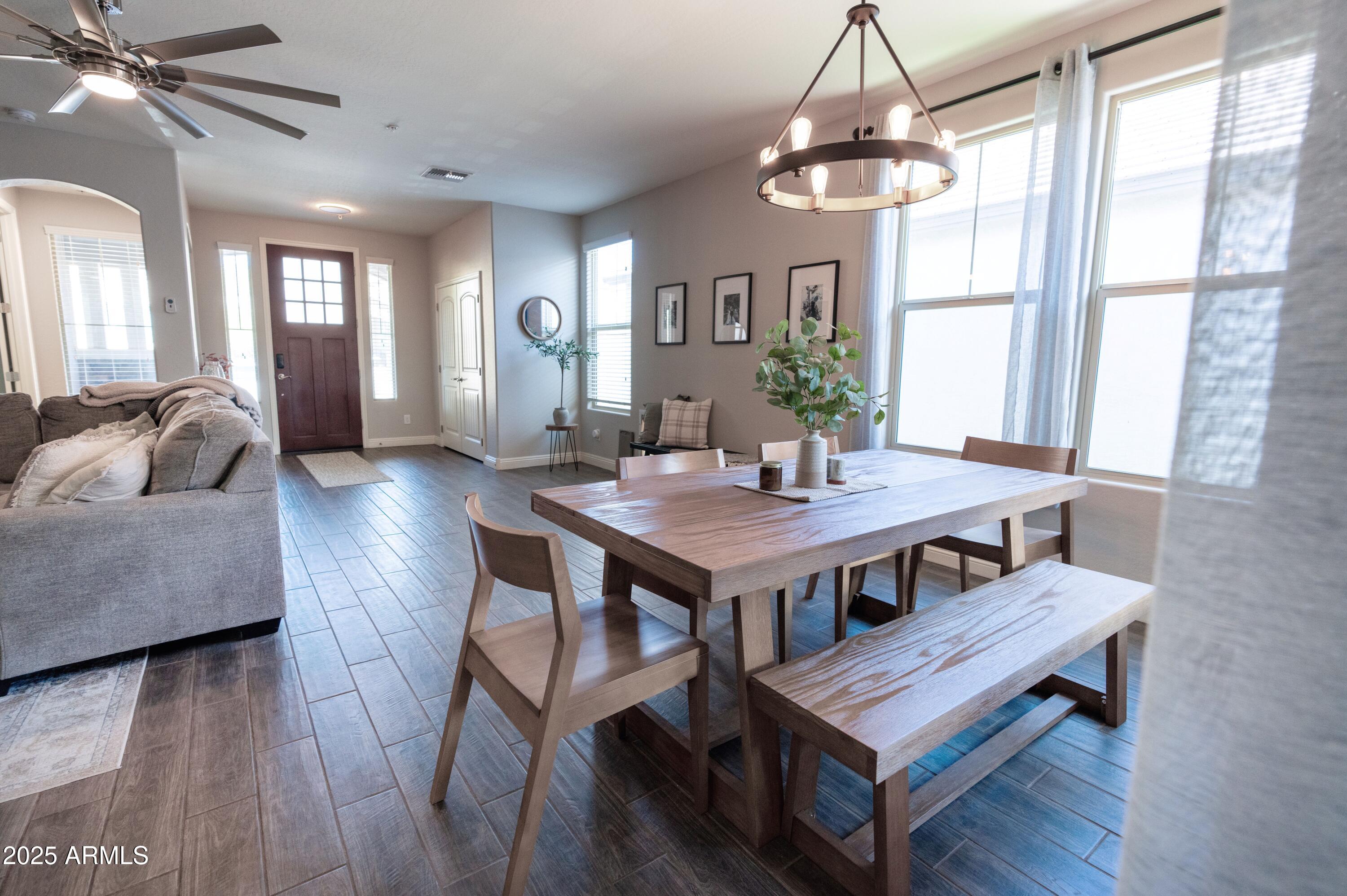 20753 West Legend Trail Buckeye, AZ 85396 - Photo 3 of 21 a dining room with wooden floor a chandelier a wooden table and chairs
