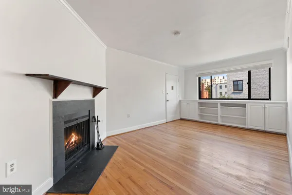 a view of an empty room with wooden floor fireplace and a window