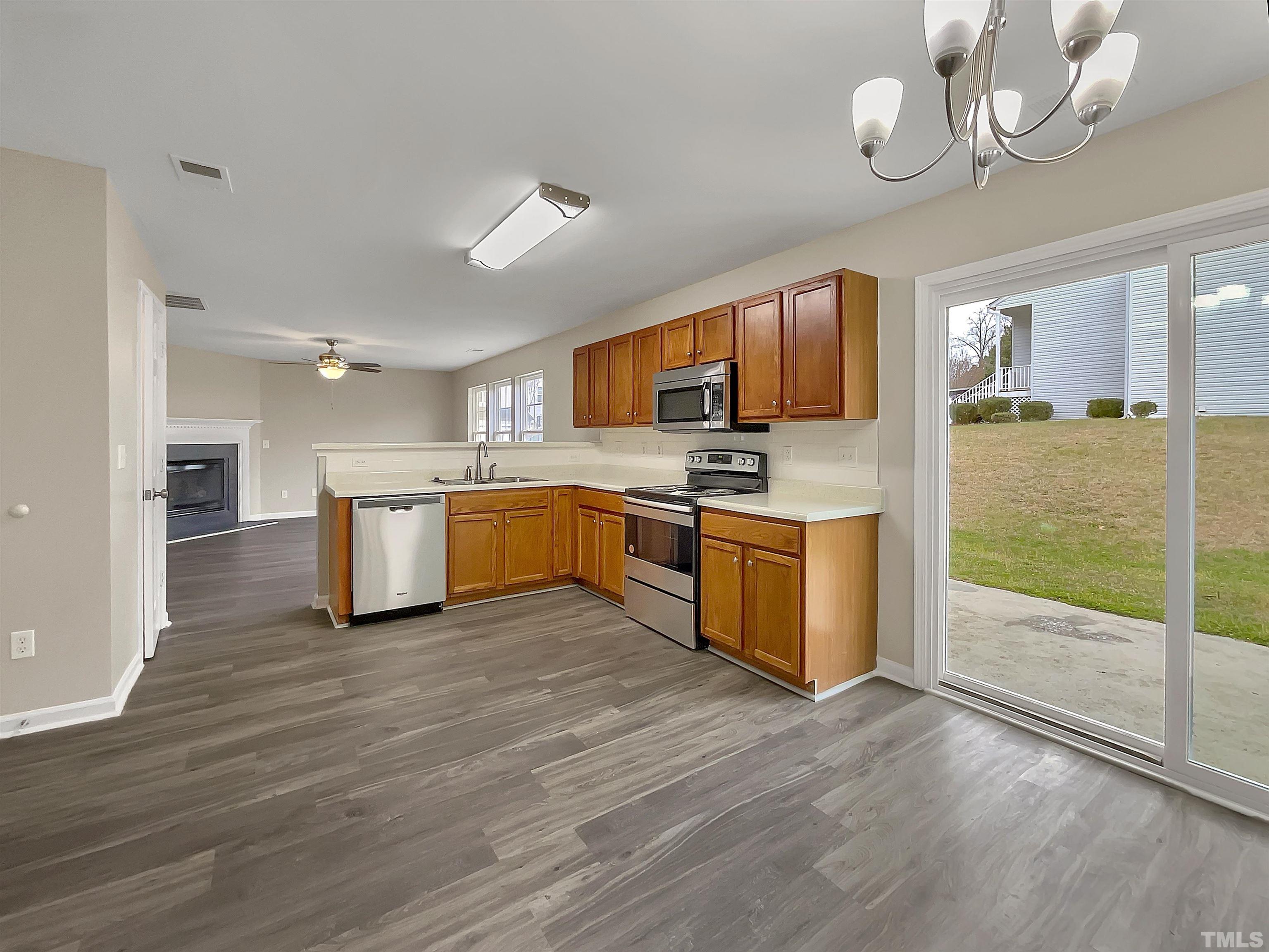 3360 Marshlane Way Raleigh, NC 27610 - Photo 2 of 17 a kitchen with stainless steel appliances granite countertop a stove top oven a sink dishwasher a refrigerator and a fireplace with wooden floor
