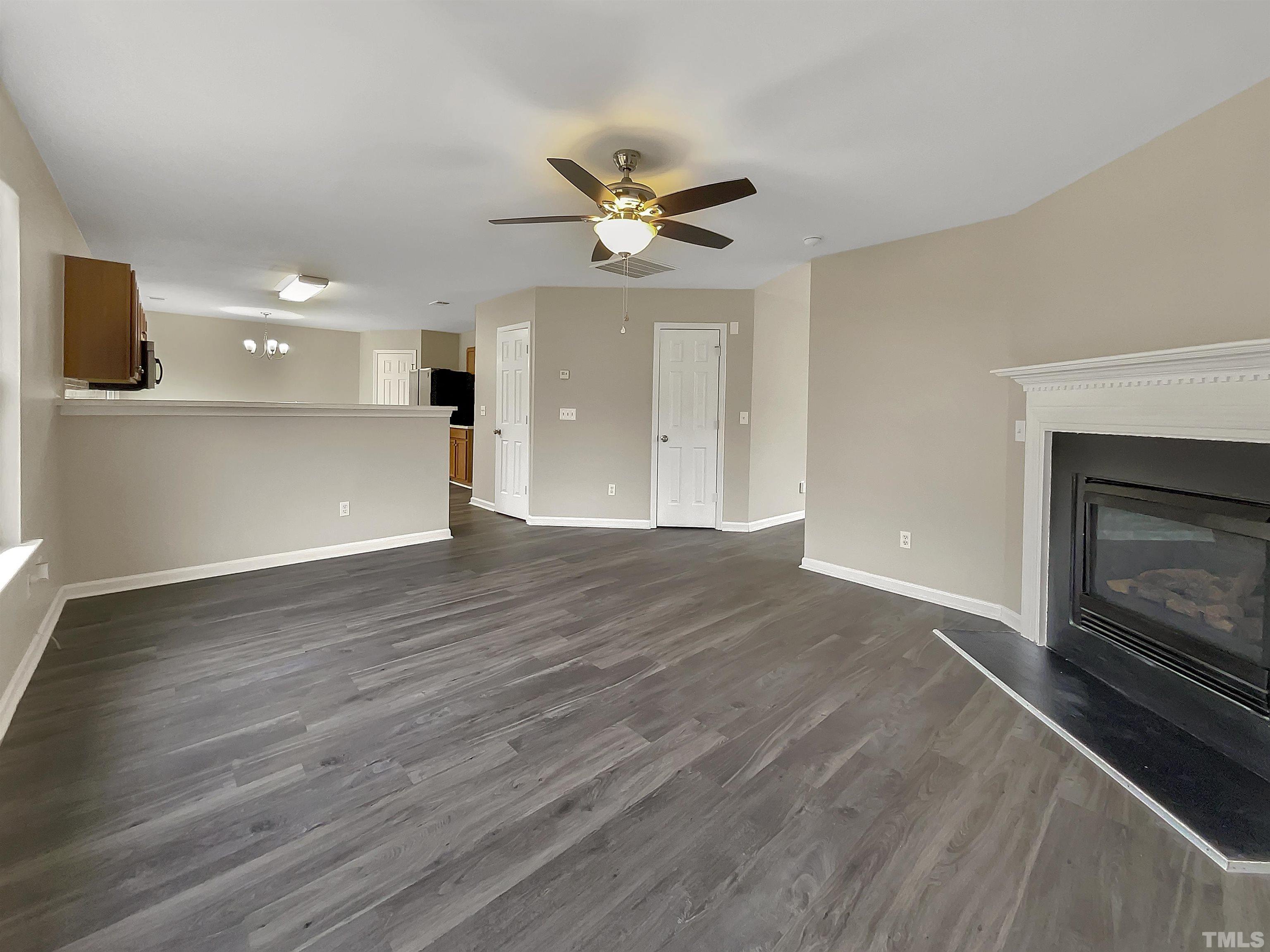 3360 Marshlane Way Raleigh, NC 27610 - Photo 8 of 17 a view of an empty room with a fireplace and a ceiling fan
