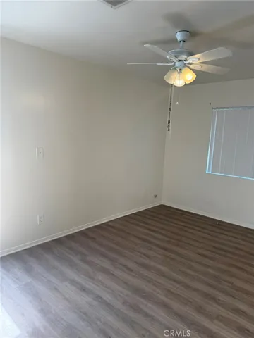 a view of an empty room with wooden floor and chandelier