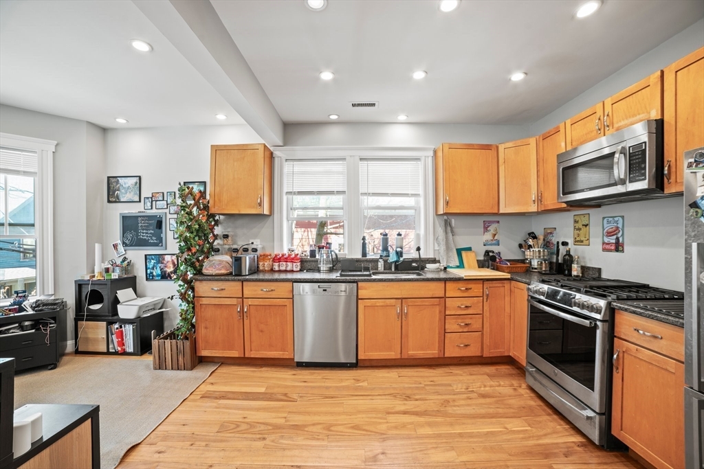 58 Weld Hill Street, Unit 2 Boston, MA 02130 - Photo 4 of 17 a kitchen with stainless steel appliances granite countertop a stove top oven a sink dishwasher a refrigerator and cabinets with wooden floor
