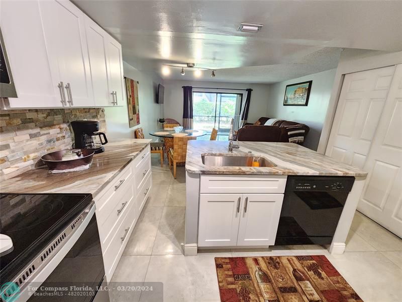 a kitchen with kitchen island granite countertop a sink stove and cabinets