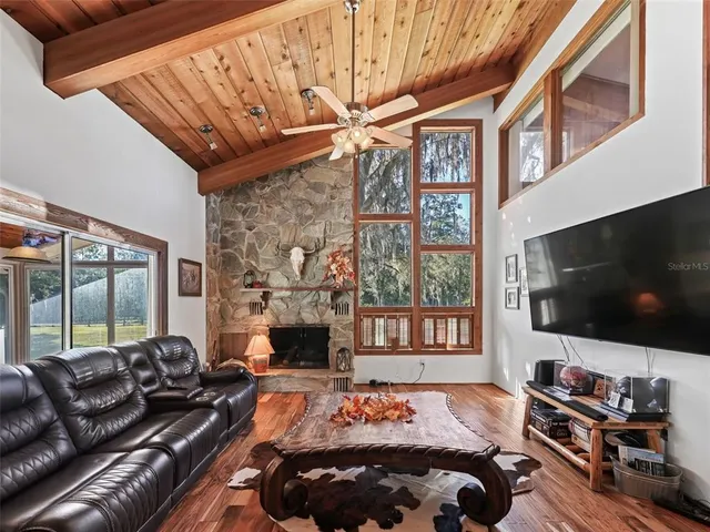 a living room with furniture a flat screen tv and a floor to ceiling window