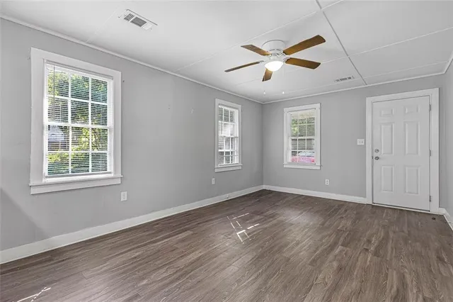 a view of an empty room with wooden floor and a window