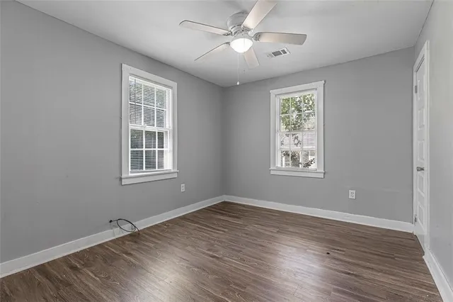 a view of empty room with wooden floor and fan