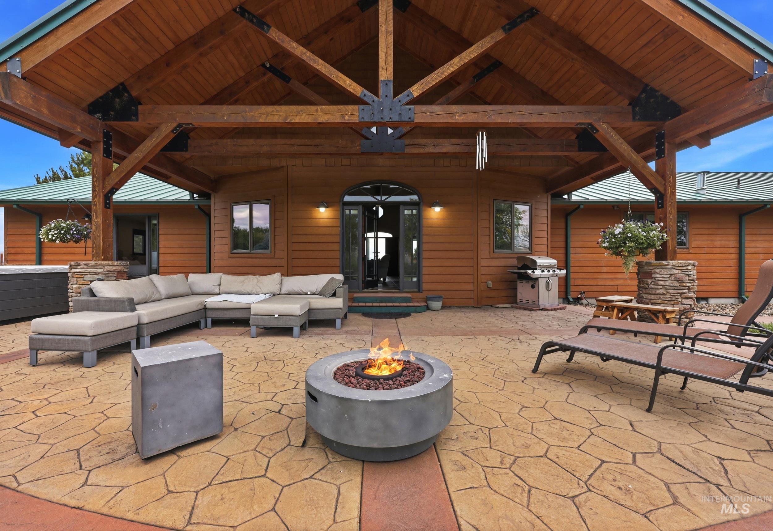 339 Airport Road Weiser, ID 83672 - Photo 31 of 49 Expansive outdoor patio featuring stamped concrete flooring, a built-in fire pit, and a prominent wood-beamed covered structure