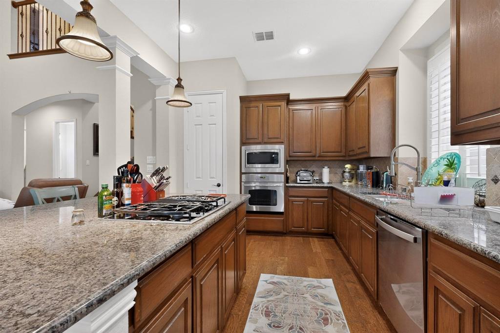 7625 Ridgedale Court Sachse, TX 75048 - Photo 10 of 40 a kitchen with stainless steel appliances granite countertop a sink stove and cabinets