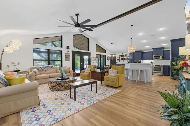 a living room with furniture kitchen view and a wooden floor