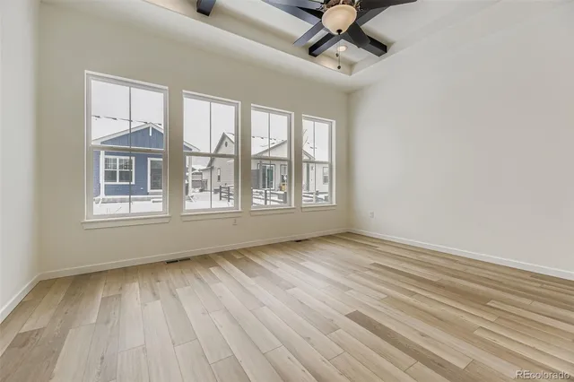 a view of an empty room with a window and wooden floor