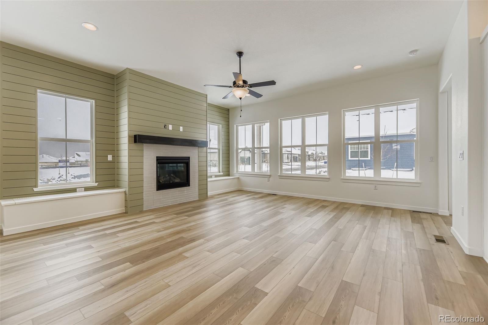 8902 South Riviera Way Aurora, CO 80016 - Photo 3 of 26 an empty room with wooden floor fireplace windows and chandelier
