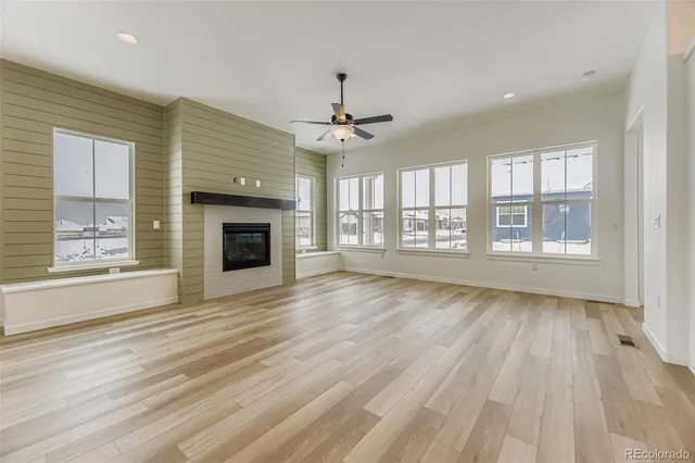 an empty room with wooden floor fireplace windows and chandelier
