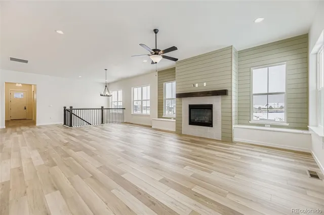 an empty room with wooden floor fireplace and windows