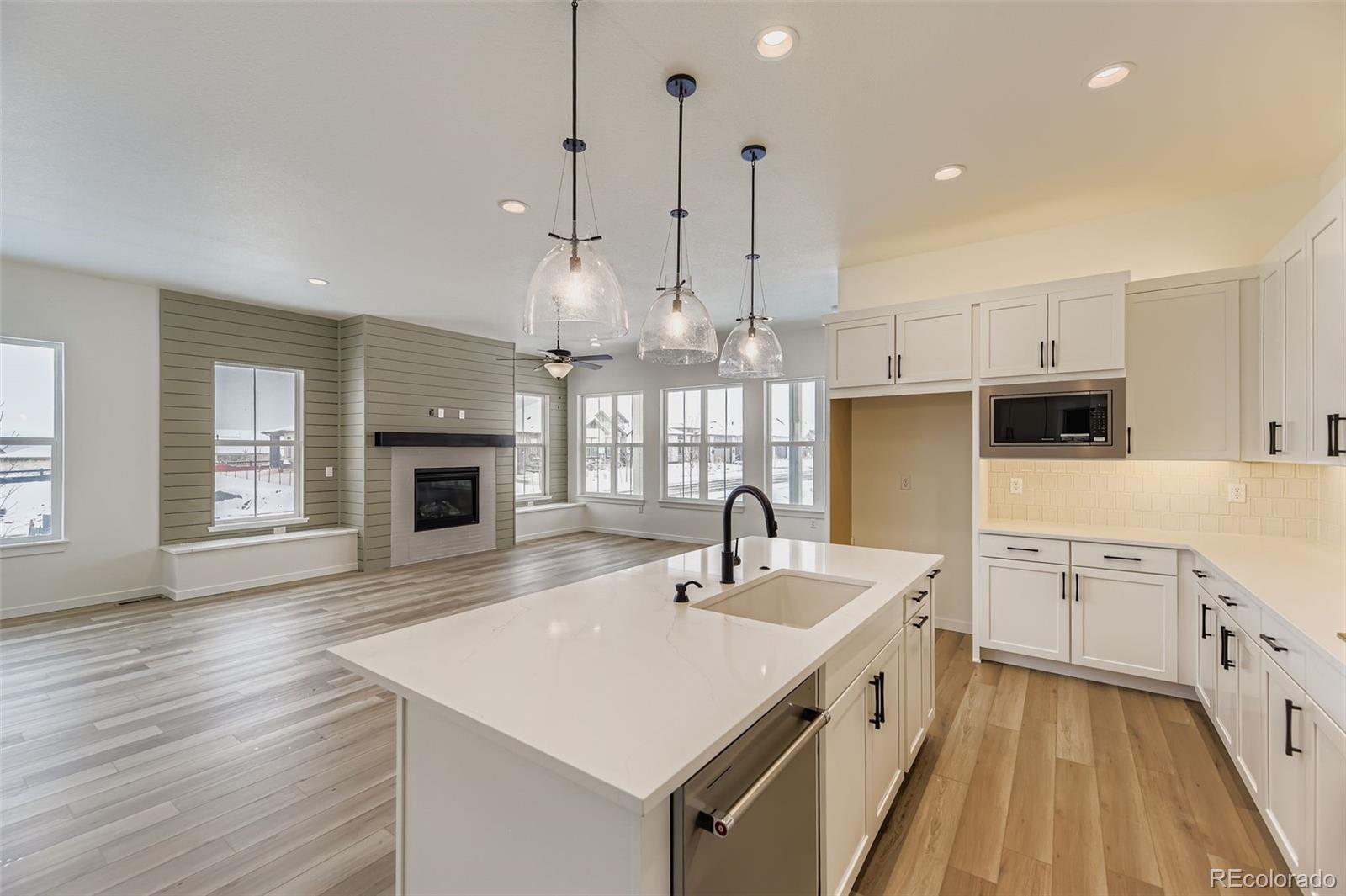 8902 South Riviera Way Aurora, CO 80016 - Photo 10 of 26 a kitchen with a sink dishwasher a stove a kitchen island with wooden floor and cabinets