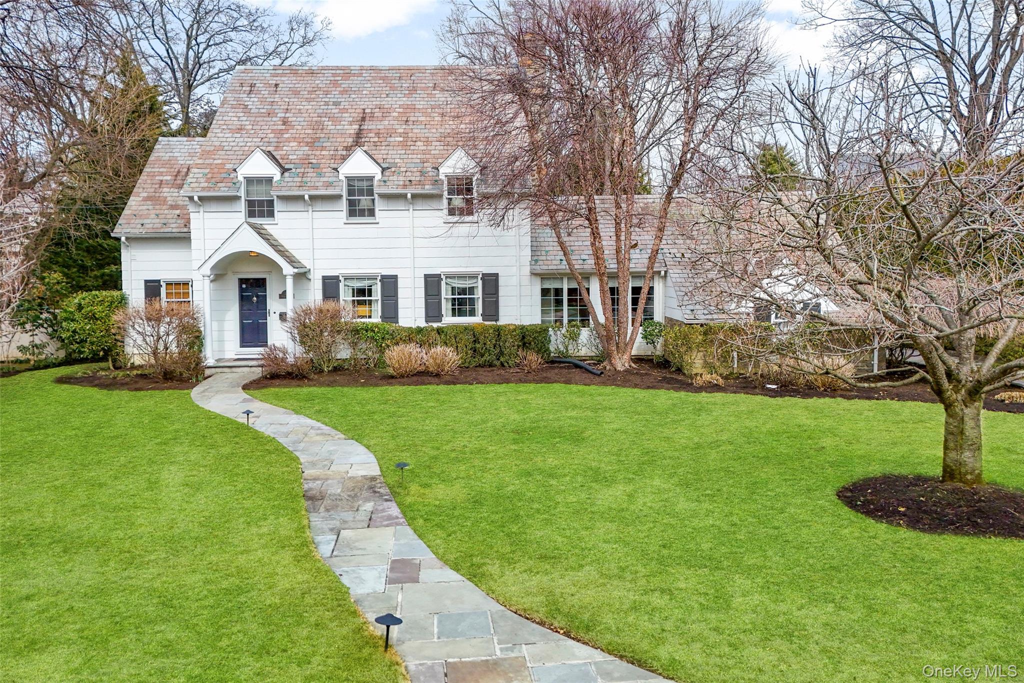 a front view of a house with a garden and trees