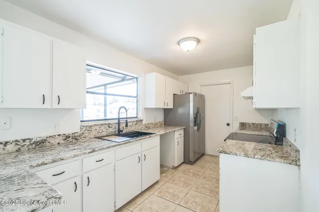 a kitchen with granite countertop a sink stove and refrigerator