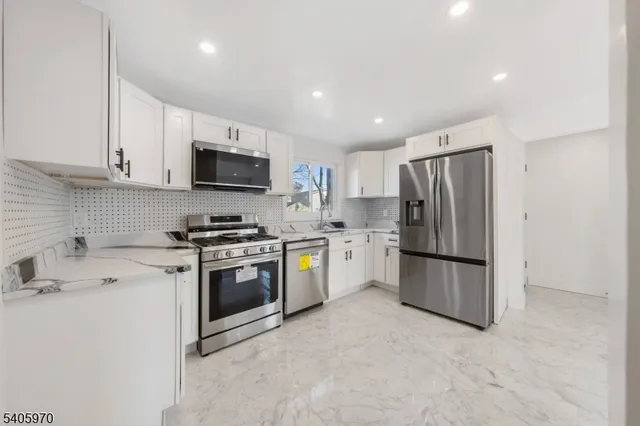 a large white kitchen with kitchen island a sink stainless steel appliances and cabinets