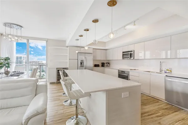 a large white kitchen with lots of counter space a sink appliances and cabinets