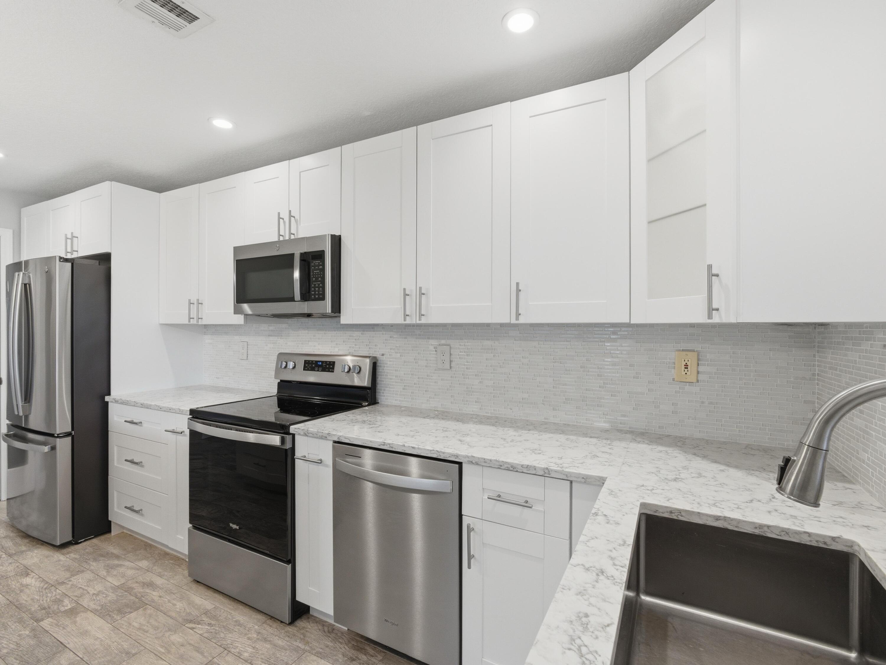 270 High Point Boulevard, Unit A Boynton Beach, FL 33435 - Photo 23 of 44 a kitchen with stainless steel appliances granite countertop white cabinets a sink a stove a microwave and a refrigerator