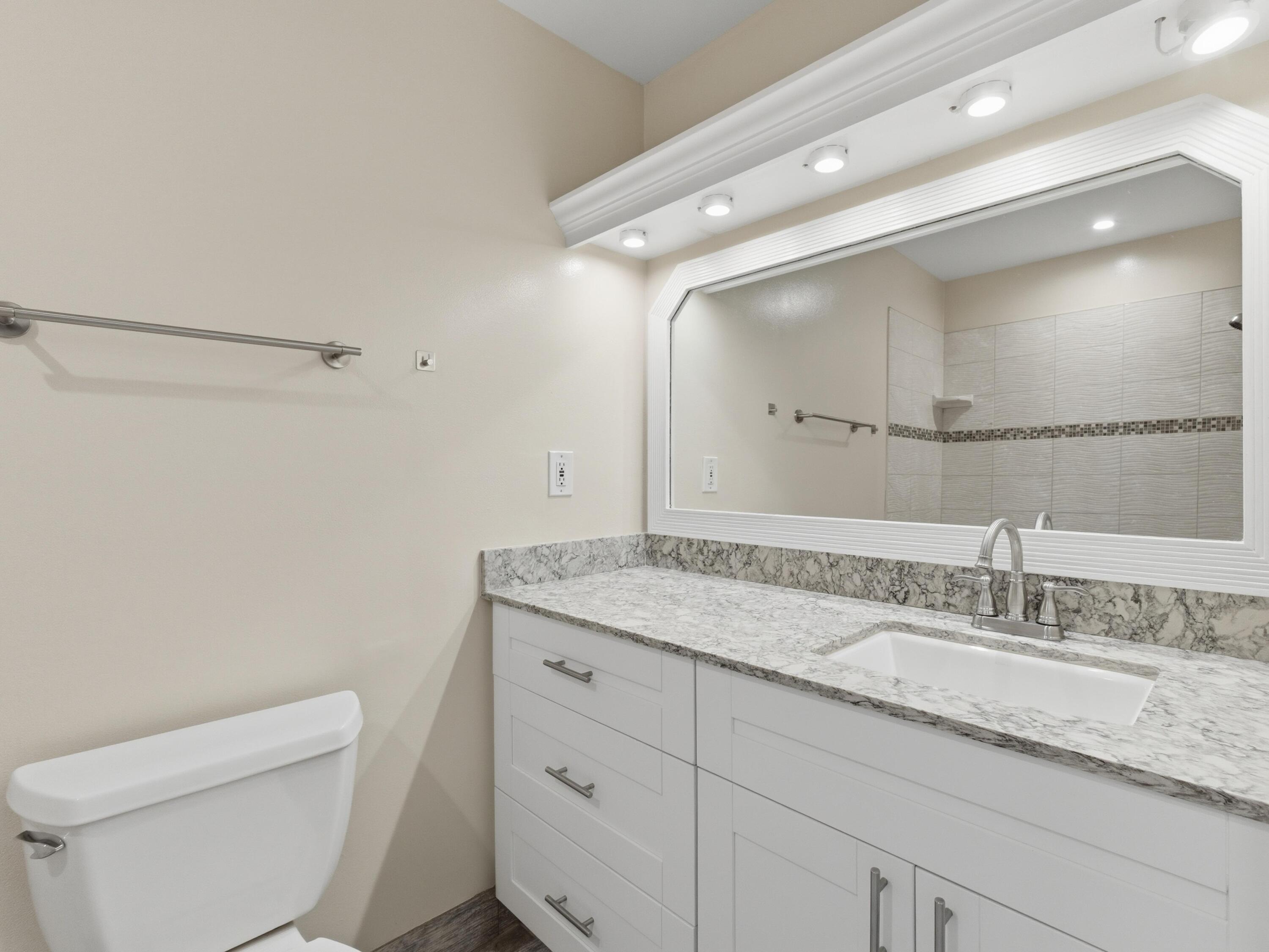 270 High Point Boulevard, Unit A Boynton Beach, FL 33435 - Photo 27 of 44 a bathroom with a granite countertop sink a toilet and a mirror